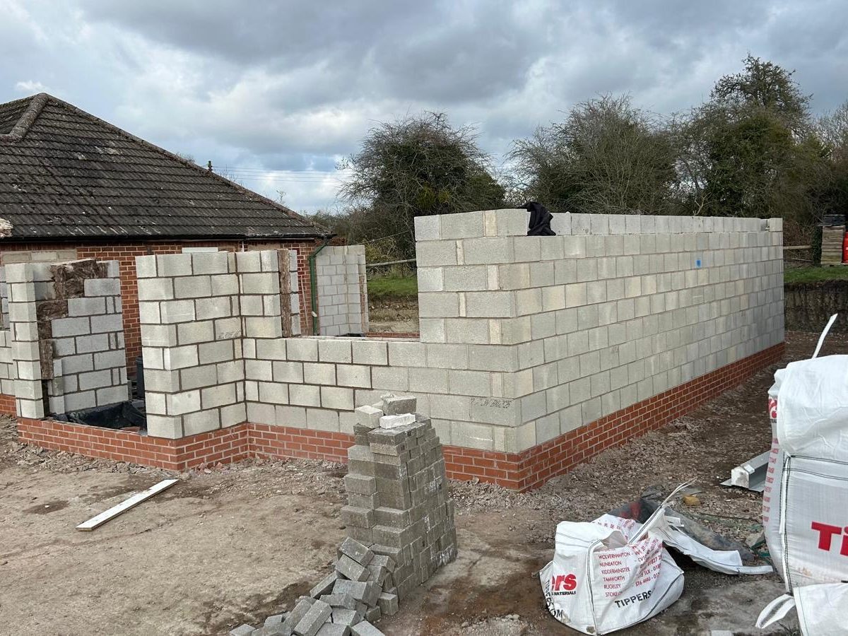 Blockwork shell of a single-storey extension on a facing brick plinth