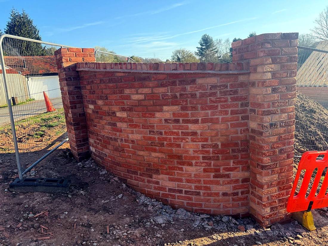 Curved feature wall in multi-red brick between two brick piers