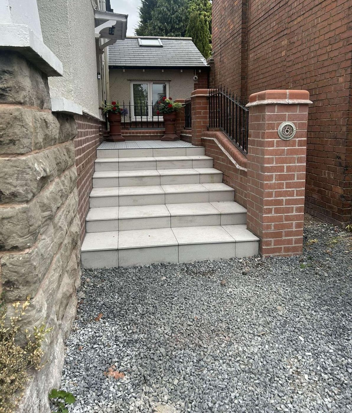 Porcelain entrance steps between brick piers and walls with black railings